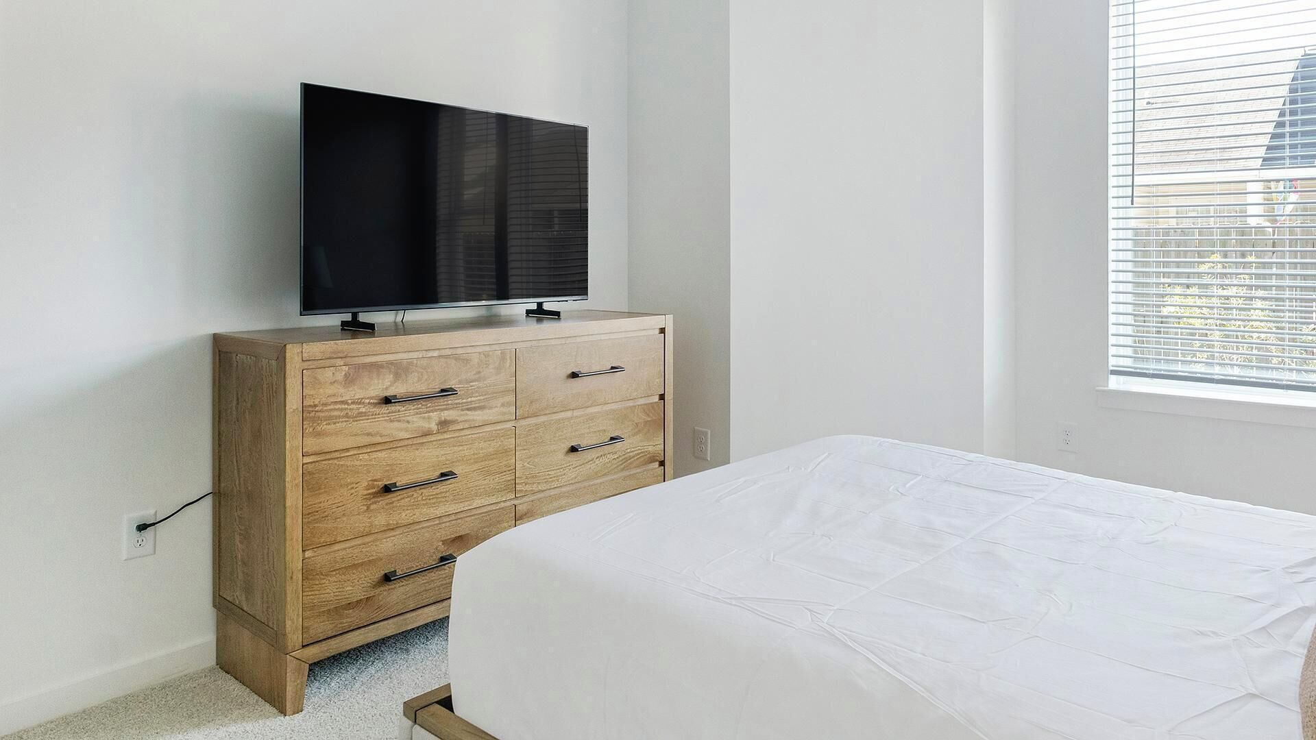 Ein Schlafzimmer mit einem Holzkapfen, einem Fernseher darauf und einem Bett mit weißer Bettwäsche.
