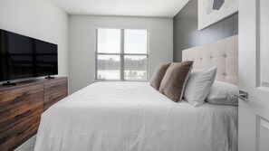 Una camera da letto con un letto grande, una televisione su una cassettiera in legno e una finestra con persiane.