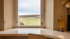 Ein Zimmer mit großem Fenster und Blick auf einen Golfplatz.