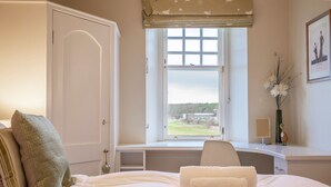 Ein Schlafzimmer mit Bett, Schreibtisch und Fenster mit Blick ins Freie.