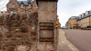 Eine Steinsäule mit Schildern, die einen Golfplatz und privaten Zugang kennzeichnen.