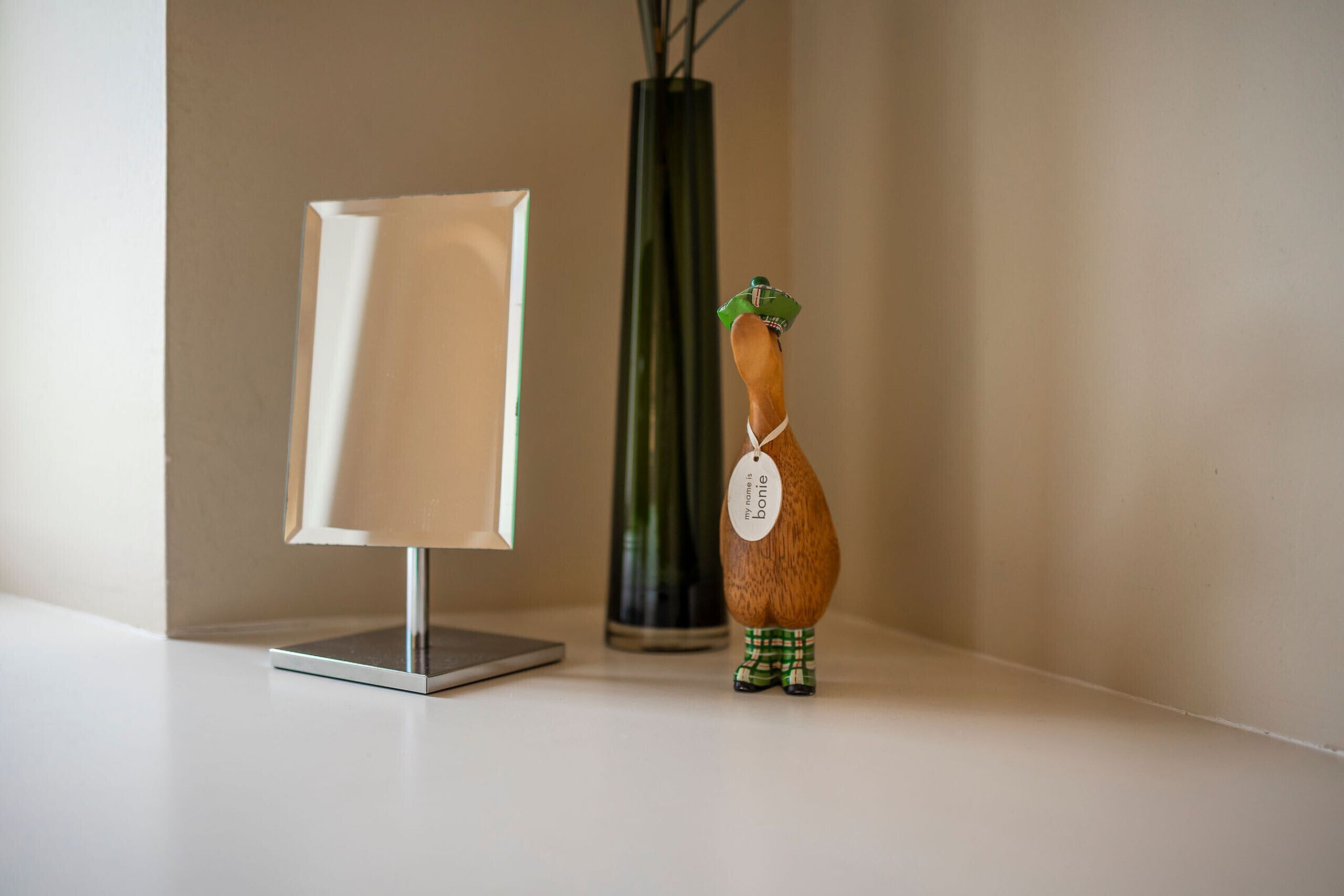 A wooden figurine with a tag, a lamp, and a vase on a white surface.