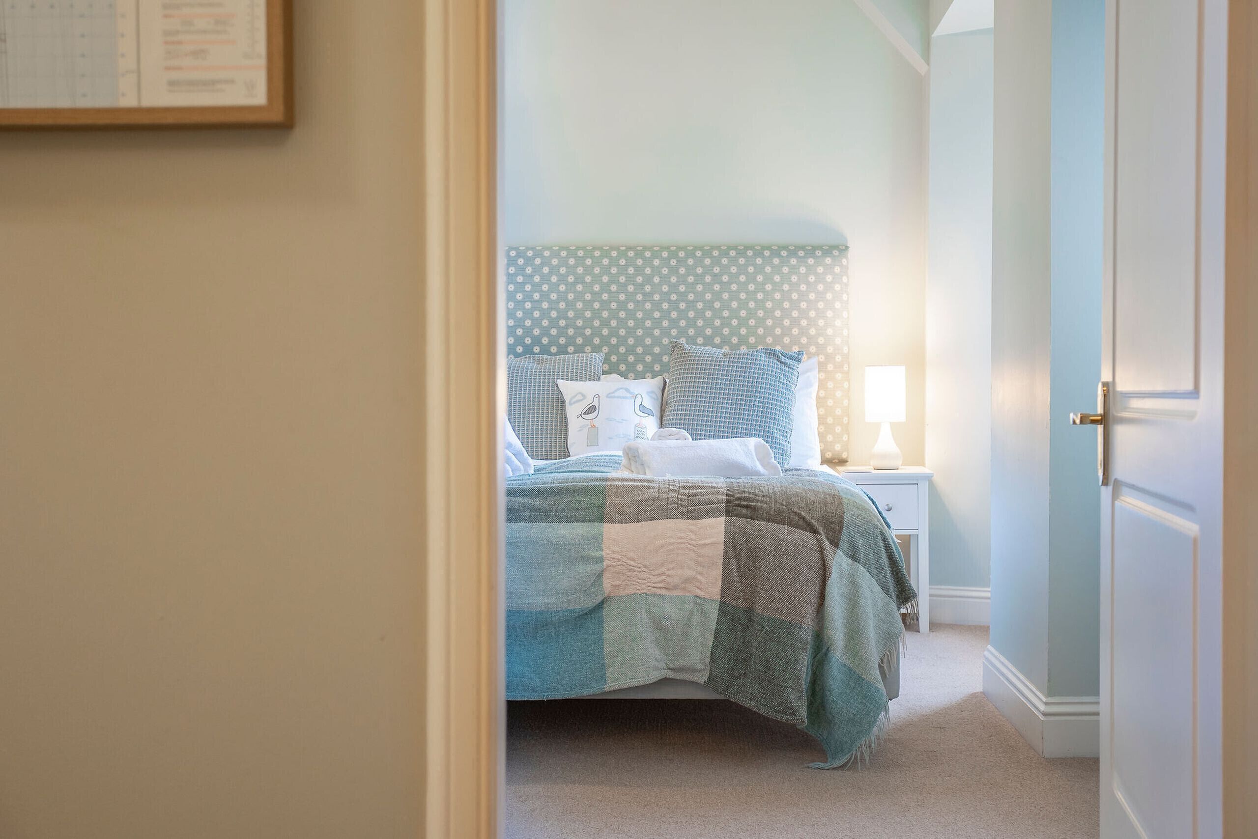 A bedroom with a bed, a nightstand, and a wall-mounted calendar.