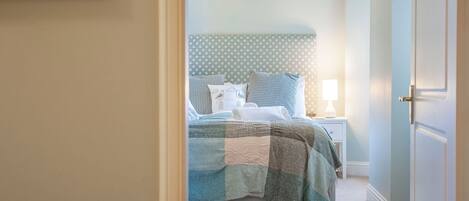 A bedroom with a bed, a nightstand, and a wall-mounted calendar.