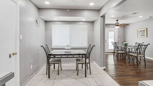 A dining area with a large table and chairs, a ceiling fan, and a window with blinds. - Casa Zen Retreat •Great Backyard• Near I-10 & Loop (El Paso)