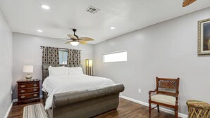 A bedroom with a bed, a wooden nightstand, a chair, a floor lamp, a ceiling fan, and a window. - Casa Zen Retreat •Great Backyard• Near I-10 & Loop (El Paso)
