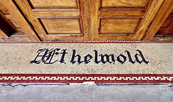 Una puerta de madera con un felpudo de mosaico que dice 'Hartheimold'.