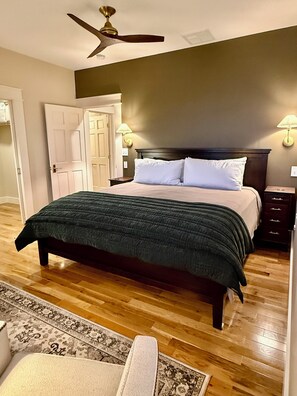 A bedroom with a bed, a ceiling fan, a nightstand, and a night lamp.