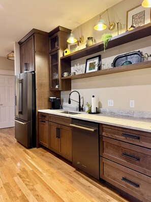 A modern kitchen with wooden cabinets, stainless steel appliances, and a marble countertop.