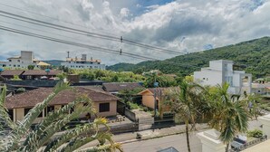 A residential area with houses, a street, and a hill in the background. - Apt w/ Barbecue 650m From the Lagoon Ruh0109 (Florianópolis)