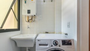 A compact laundry room with a washing machine, a sink, and a water heater. - Apt w/ Barbecue 650m From the Lagoon Ruh0109 (Florianópolis)