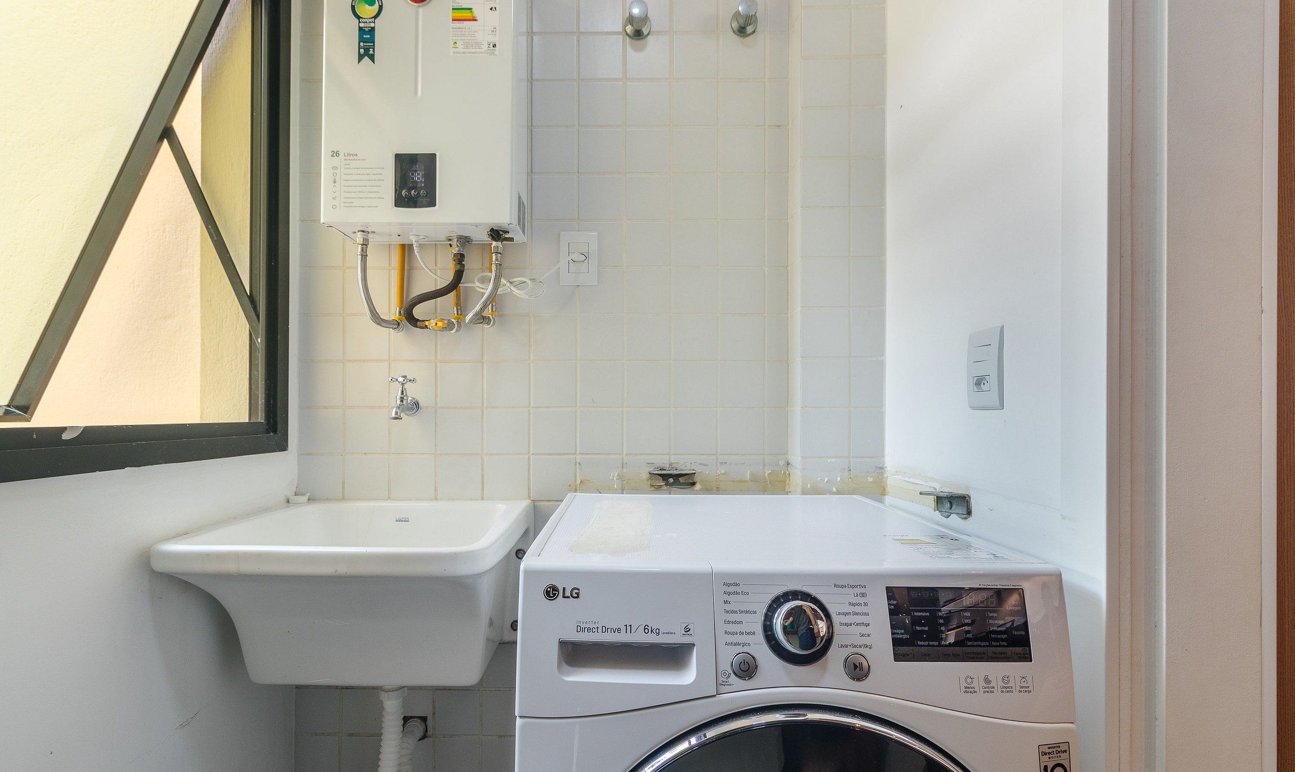 Une petite buanderie équipée d’un lave-linge, d’un évier et d’un chauffe-eau.