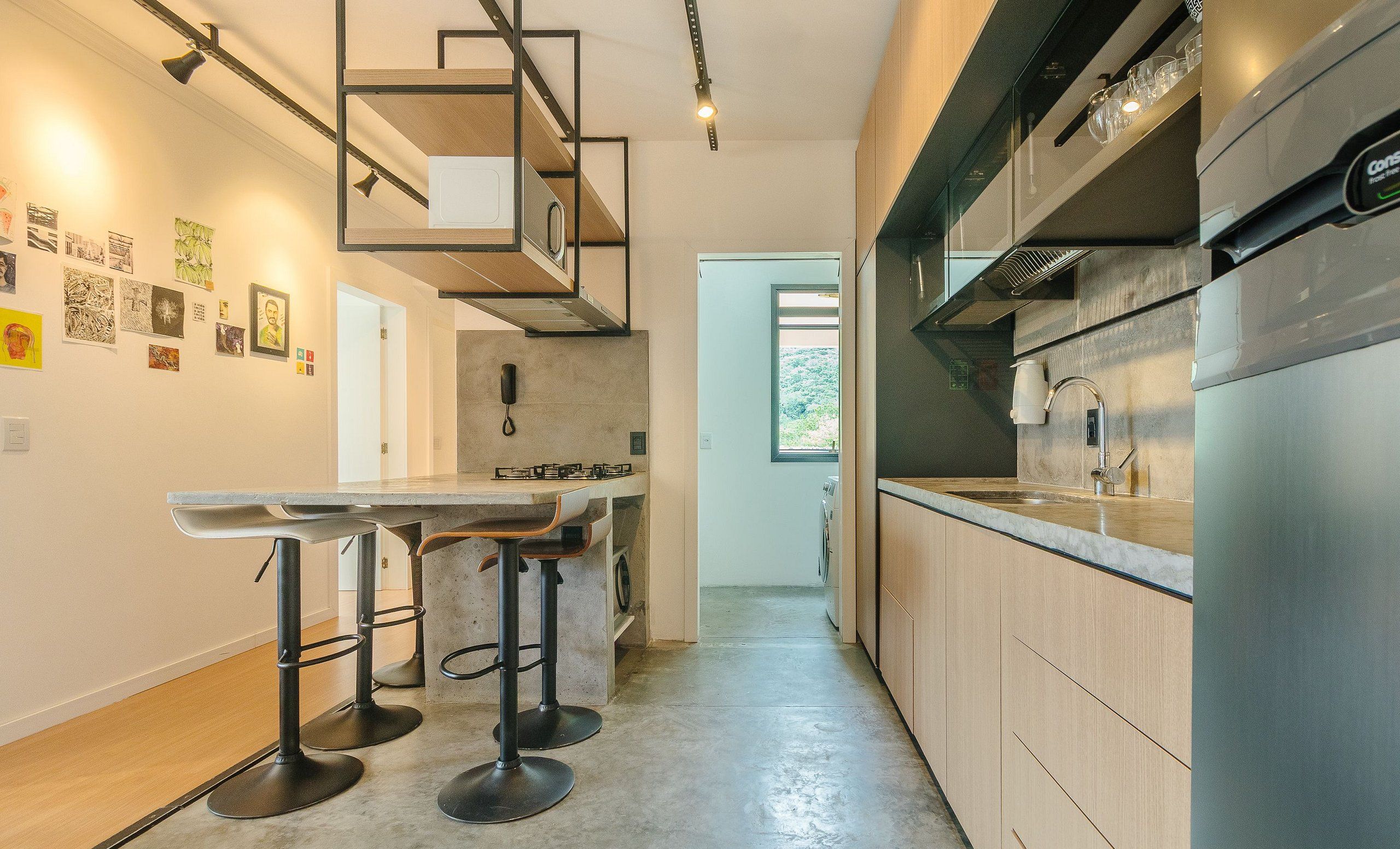 Une cuisine moderne dotée d’un îlot central, de tabourets de bar et d’un four encastré.