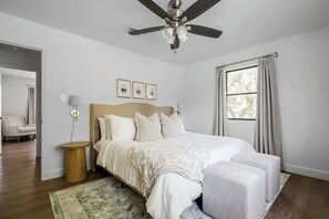 A bedroom with a bed, bedside tables, a ceiling fan, and a window with curtains. - Suniland w/Pool, Hot-tub and sauna! (Fredericksburg)