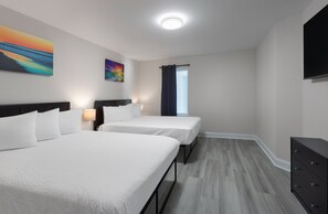 Ein Hotelzimmer mit zwei Betten, einem Flachbildfernseher, einem Schminktisch und Bildern an den Wänden.