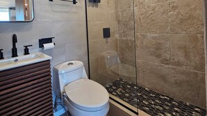 Un baño moderno con inodoro, lavamanos y cabina de ducha de vidrio.