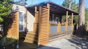 Eine Holzhütte mit Veranda, einer kleinen Terrasse und einem überdachten Bereich.