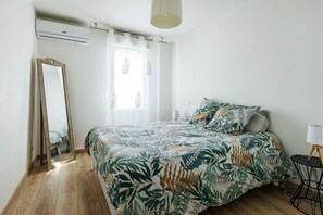 Ein Schlafzimmer mit Bett, Spiegel, Nachttisch und Lampe.
