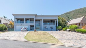 Ein modernes, zweistöckiges Gebäude mit Garage, kleinem Rasen und einer sanften Hügelkulisse im Hintergrund.