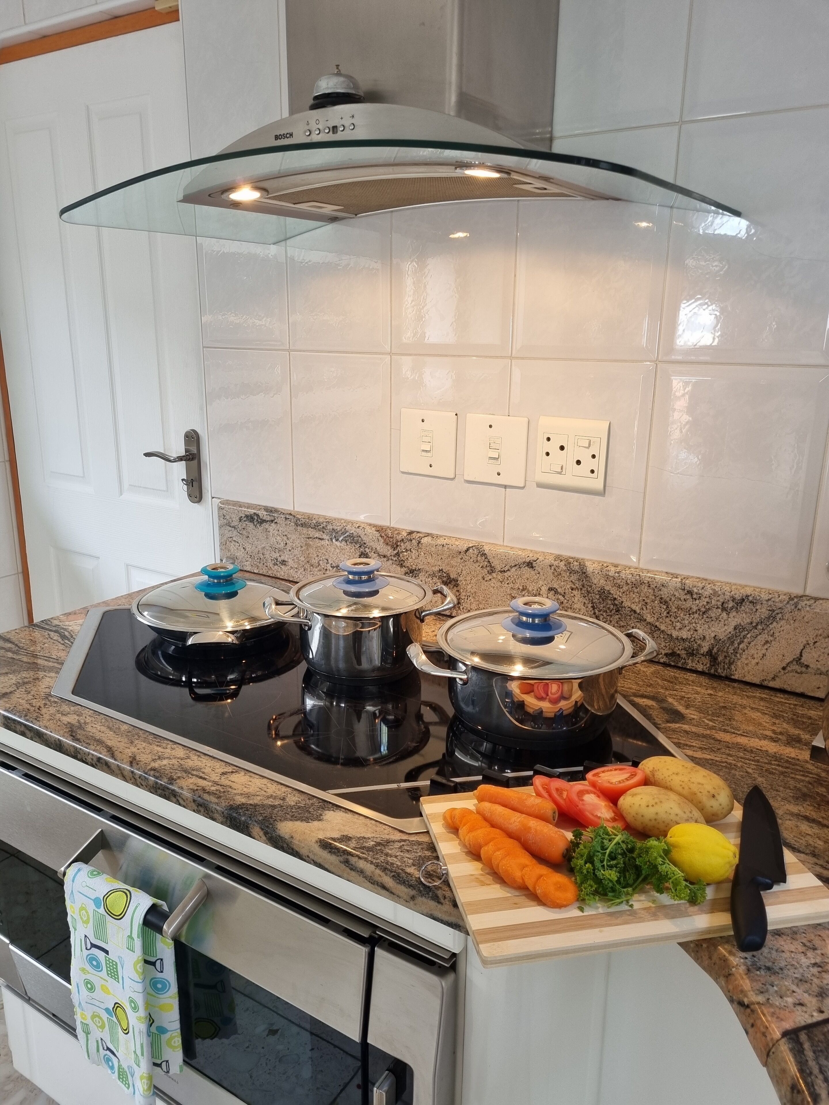 Une cuisine équipée d’une cuisinière, de casseroles, d’une planche à découper avec des légumes et d’un couteau.