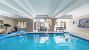 Ein Hallenbad mit blauem Boden, einem Laufband und einem Sessel am Fenster.
