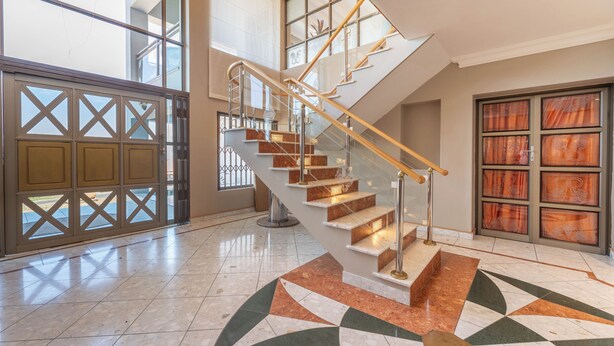 Eine imposante Treppe mit Glastrennwand, die zu einer oberen Etage führt.