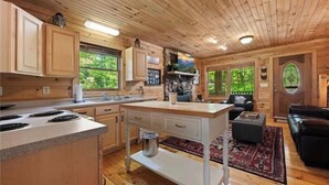 Een chaletinterieur met houten wanden en plafond, een keuken met een granieten aanrecht en een woonruimte met een leren bank.