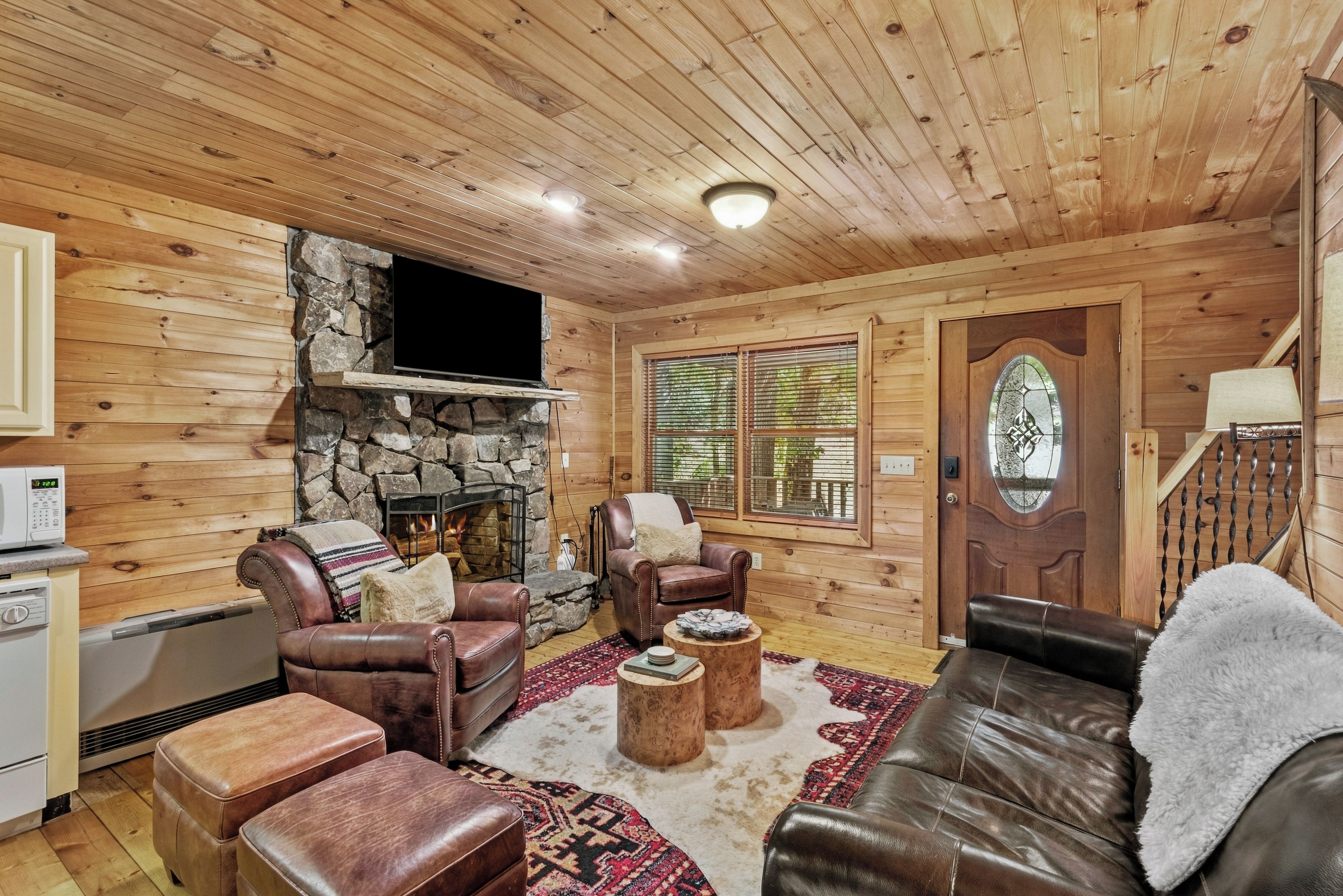 L’intérieur chaleureux d’un chalet en rondins, avec une cheminée en pierre, des meubles en cuir et un plafond en bois.