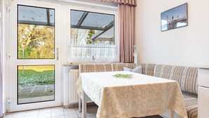 Una habitación con una mesa, asientos tipo banco y vistas a través de una puerta de vidrio.