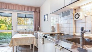 Una cocina compacta con estufa a gas, pileta y zona de comedor con mesa y sillas.