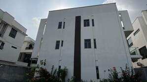 A modern building with a central vertical feature, surrounded by a paved area with plants. - ETD SUPPORT (Lekki)