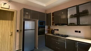 A modern kitchen with a built-in oven, microwave, and stainless steel refrigerator. - ETD SUPPORT (Lekki)