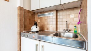 Een kleine keuken met een fornuis, spoelbak en een afzuigkap boven de tegels.
