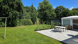 A backyard with a patio, a table, and chairs. - Apartment "Souterrain" with Private Terrace, Garden, and Wi-Fi (Cuxhaven)