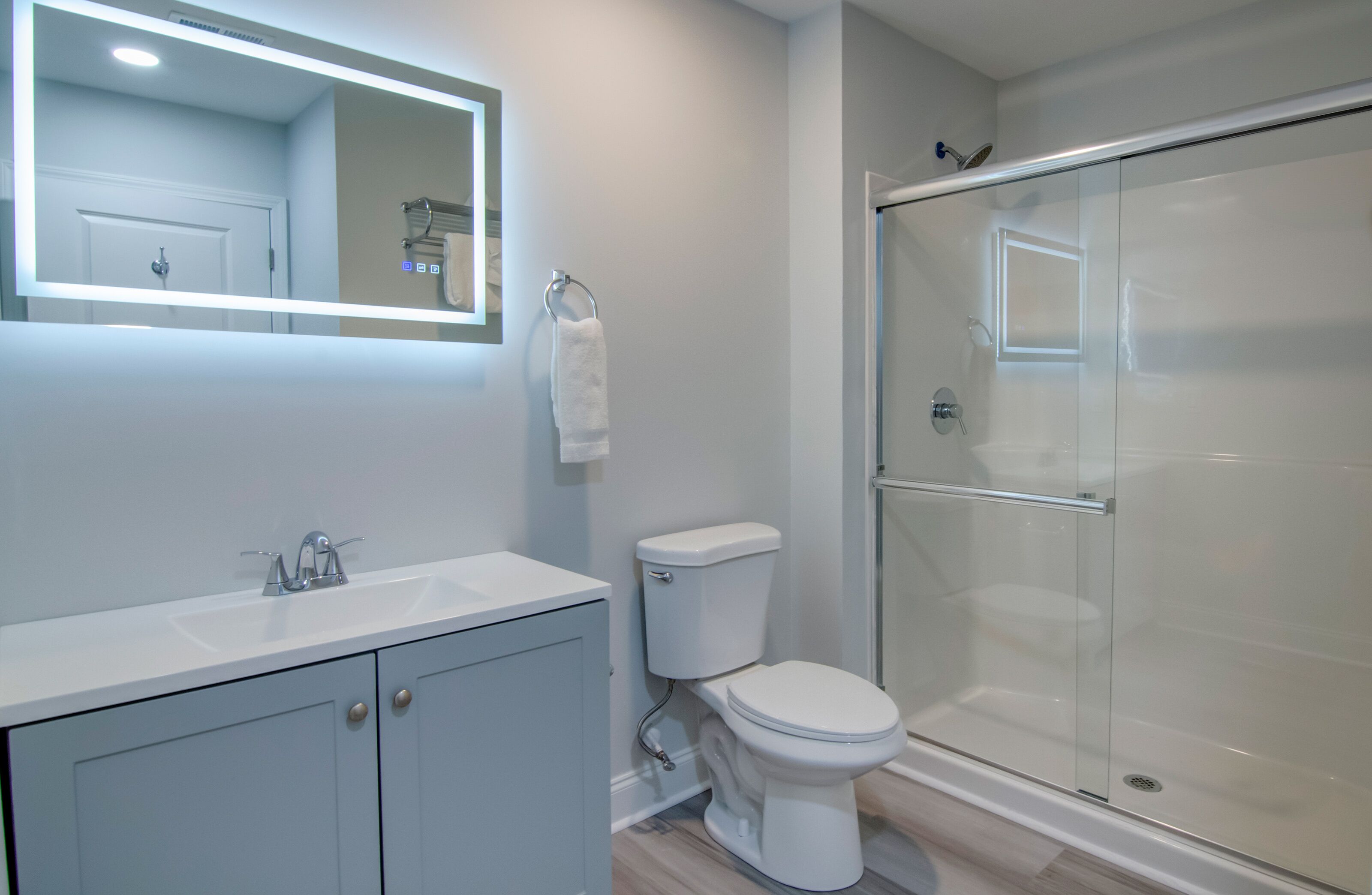 Un baño moderno con lavamanos blanco, inodoro y cabina de ducha de vidrio.