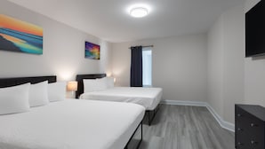 Hotellihuone, jossa on kaksi sänkyä, taulutelevisio, lipasto ja taideteoksia seinillä.