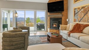 Ein Wohnzimmer mit Kamin, einer Couch, einem Sessel, einem Couchtisch und einem Fernseher.