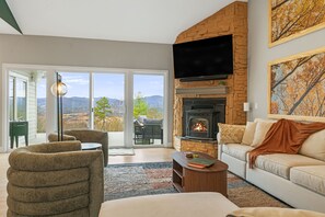Ein Wohnzimmer mit Kamin, einer Couch, einem Sessel, einem Couchtisch und einem Fernseher.