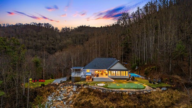 Ein zweistöckiges Haus mit überdachter Veranda, Swimmingpool und gepflegtem Rasen.