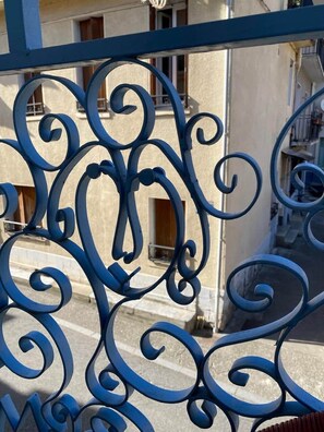 A blue metal gate with intricate designs. - Jasmine, pretty hat. The breath of fresh air. (Bagnères-de-Luchon)