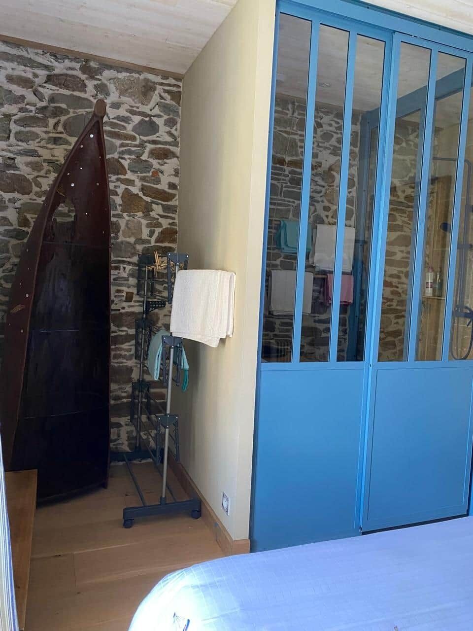 Ein Zimmer mit Steinwand, einem blauen Kleiderschrank, einer Holztür und einem Metalldörrgestell.