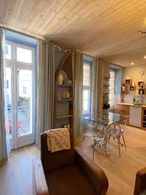 A cozy living room with a glass dining table, a sofa, and a kitchen area with a dishwasher. - Jasmine, pretty hat. The breath of fresh air. (Bagnères-de-Luchon)