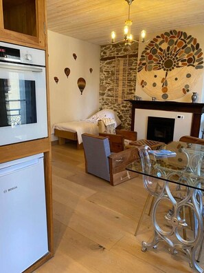 A cozy living room with a fireplace, a dining area with a glass table, and a kitchen with a Bosch refrigerator. - Jasmine, pretty hat. The breath of fresh air. (Bagnères-de-Luchon)