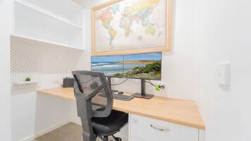 Ein Arbeitsplatz mit Schreibtisch, Stuhl, Computer und einer Weltkarte an der Wand.