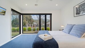 Ein Schlafzimmer mit einem großen Bett, Blick ins Freie und einem Fenster.