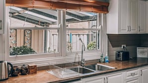 Eine Küche mit Fenster, Spüle und Arbeitsplatte mit Wasserkocher und Gläsern.