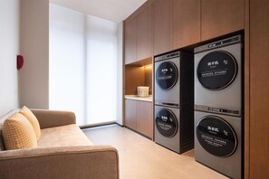 A modern room with built-in appliances, including a dryer and washer, and a sofa. - Hilton Garden Inn Chongqing Bishan (Chongqing)