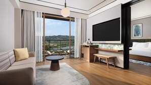 Une chambre d’hôtel moderne dotée d’une grande télévision, d’un canapé, d’une table à manger et d’un balcon avec vue.