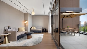 Un salon moderne avec un canapé, une table basse et un coin repas comprenant des chaises et un parasol.