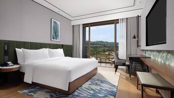 Une chambre d’hôtel avec un grand lit, un bureau, une chaise, une télévision et une vue sur l’extérieur.